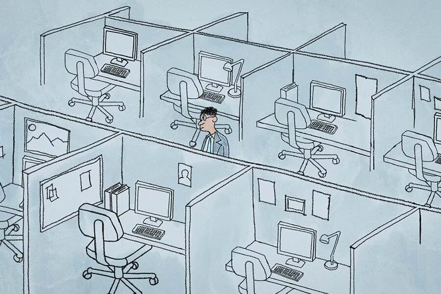 An office worker standing alone amid eight empty cubicles. 