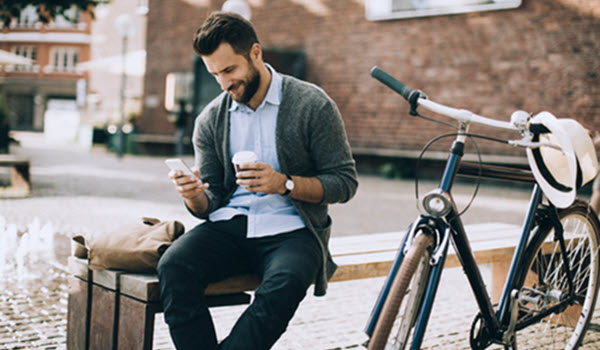 man sitting outside on bench looking at mobile phone